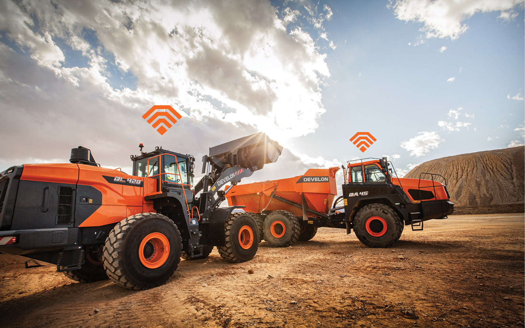 A DEVELON wheel loader and articulated dump truck using construction equipment telematics on the job site
