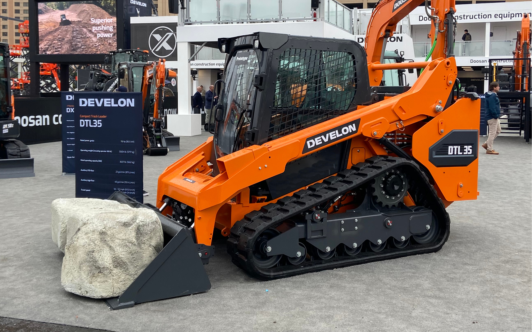 Alt Text: A DEVELON compact track loader and bucket attachment on display at CONEXPO-CON/AGG.