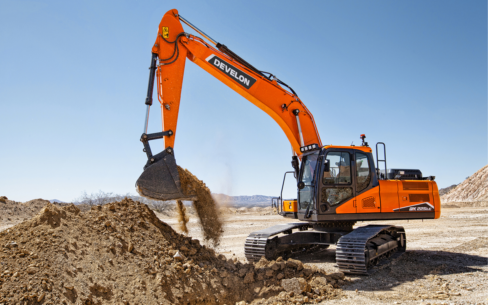 A DEVELON wheel excavator scooping dirt on a job site.