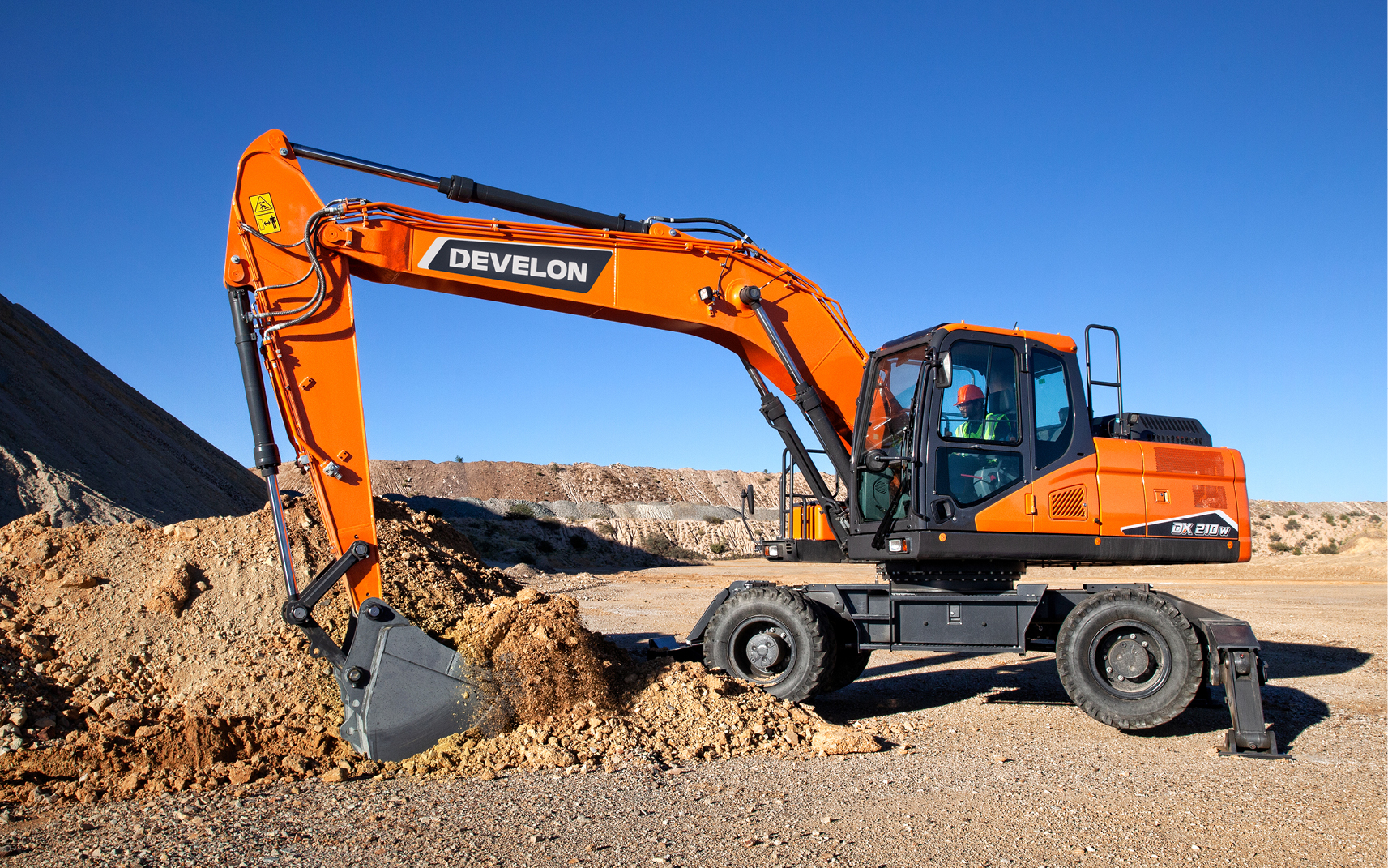 A DEVELON wheel excavator scooping dirt on a job site.